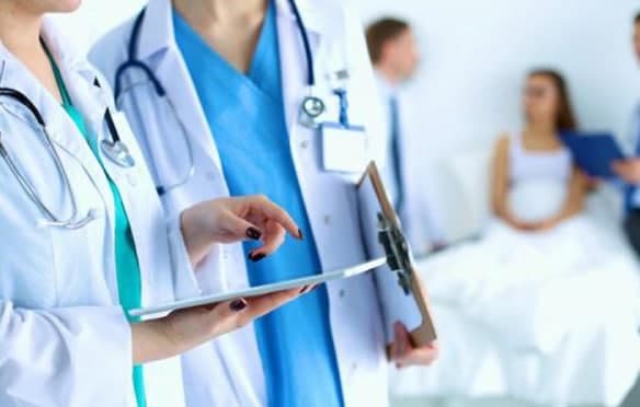 Two clinicians reviewing a chart together at a patient bedside